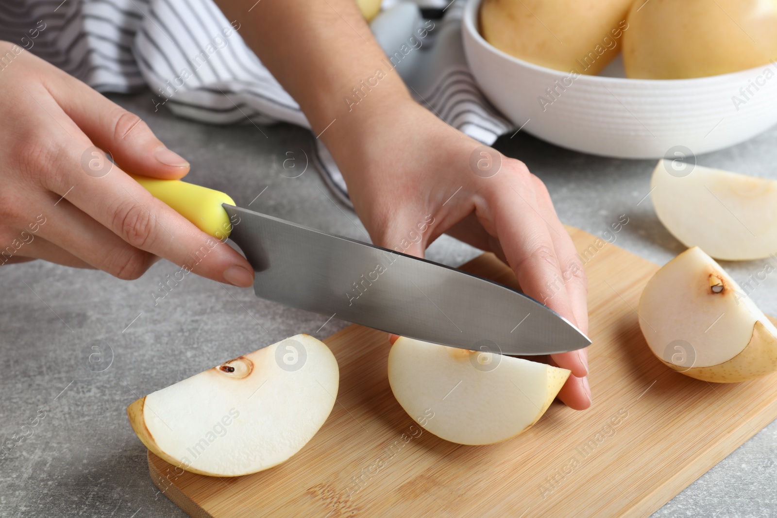 Photo of Woman cutting apple pear at grey table, closeup