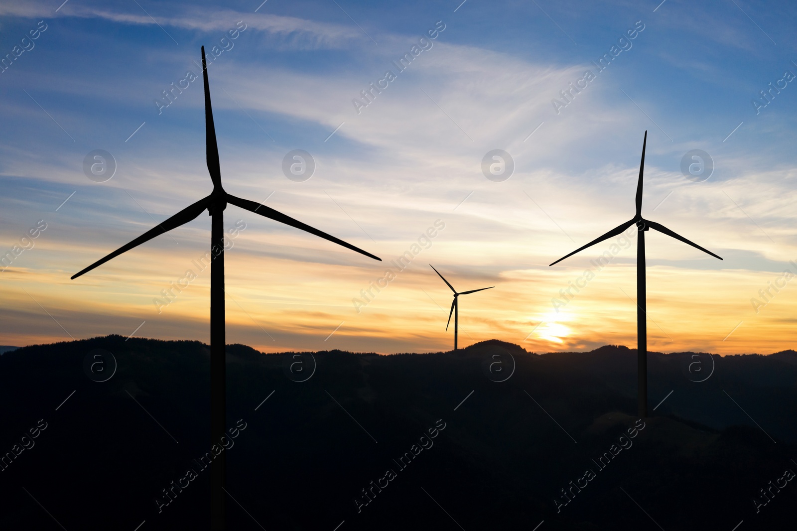 Image of Modern wind turbines in mountains at sunset. Alternative energy source