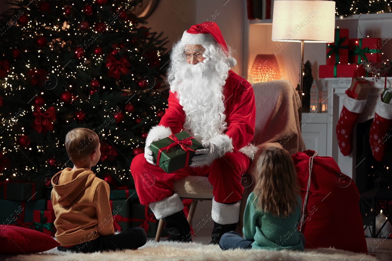 Photo of Merry Christmas. Santa Claus giving present to children at home