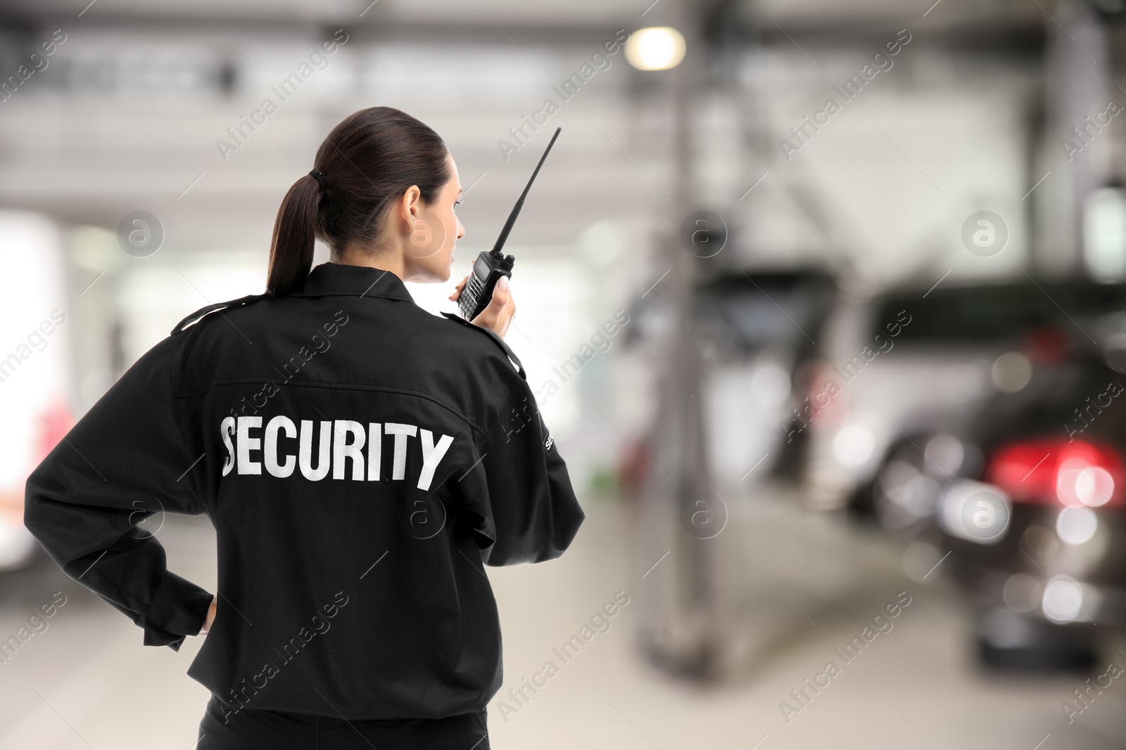 Image of Security guard using portable radio transmitter in automobile repair shop, space for text