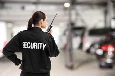 Security guard using portable radio transmitter in automobile repair shop, space for text