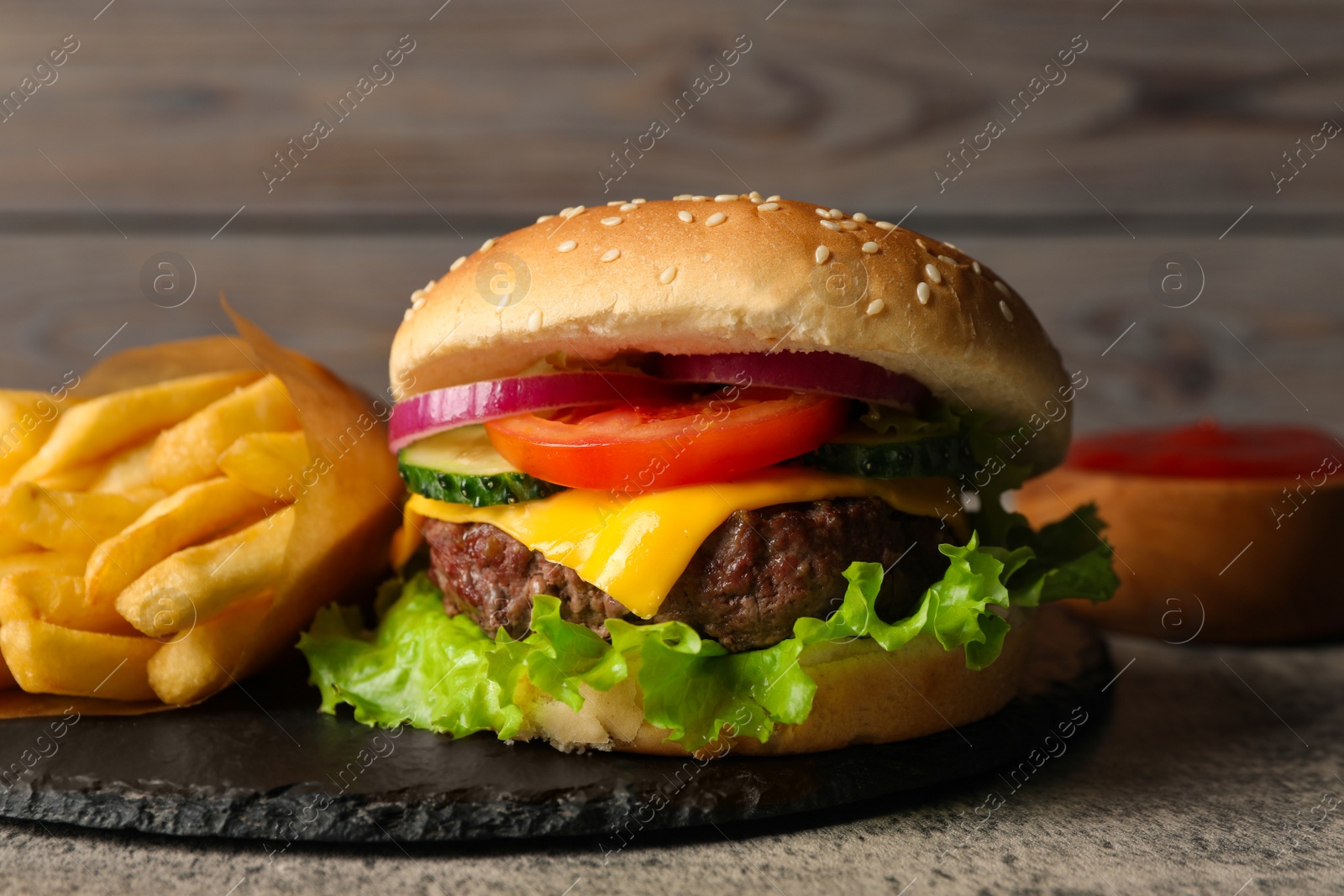 Photo of Delicious burger and french fries served on grey table, closeup