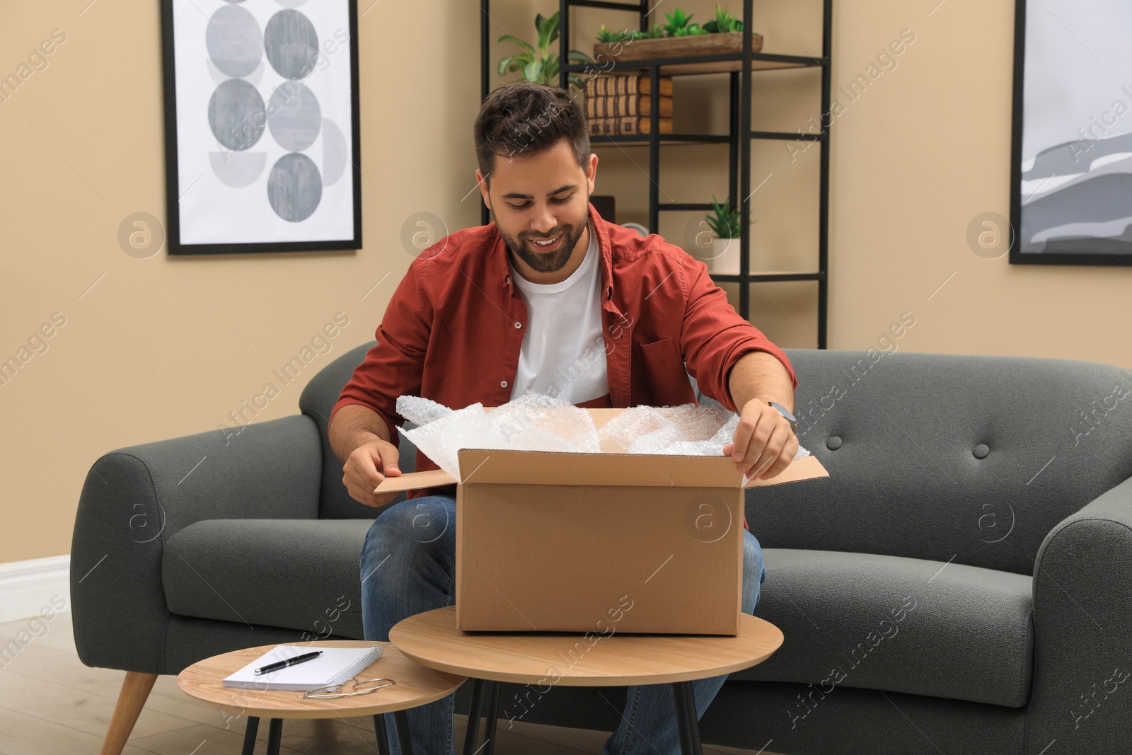 Photo of Man unpacking parcel at home. Online shopping