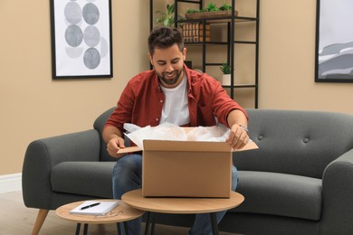 Photo of Man unpacking parcel at home. Online shopping