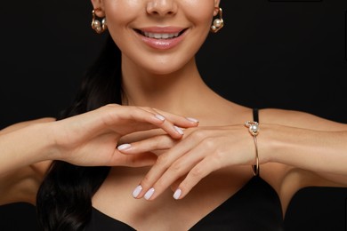 Photo of Young woman wearing elegant pearl jewelry on black background, closeup