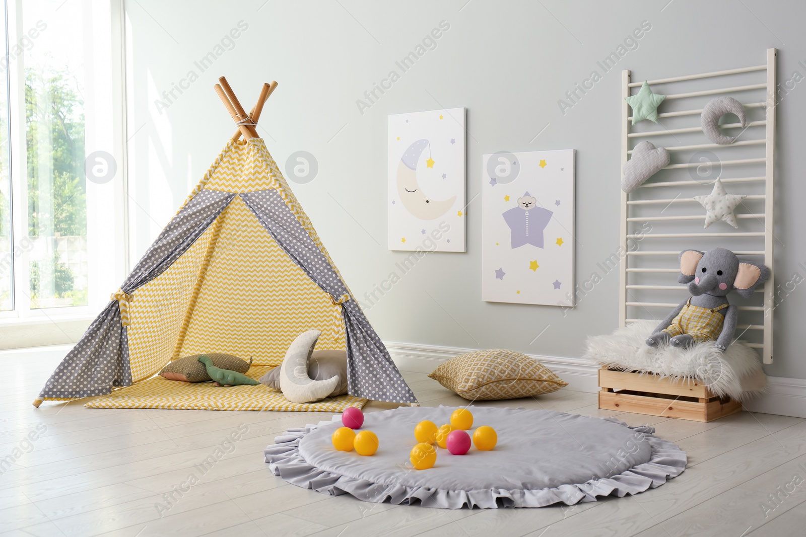 Photo of Stylish child's room interior with adorable paintings and play tent