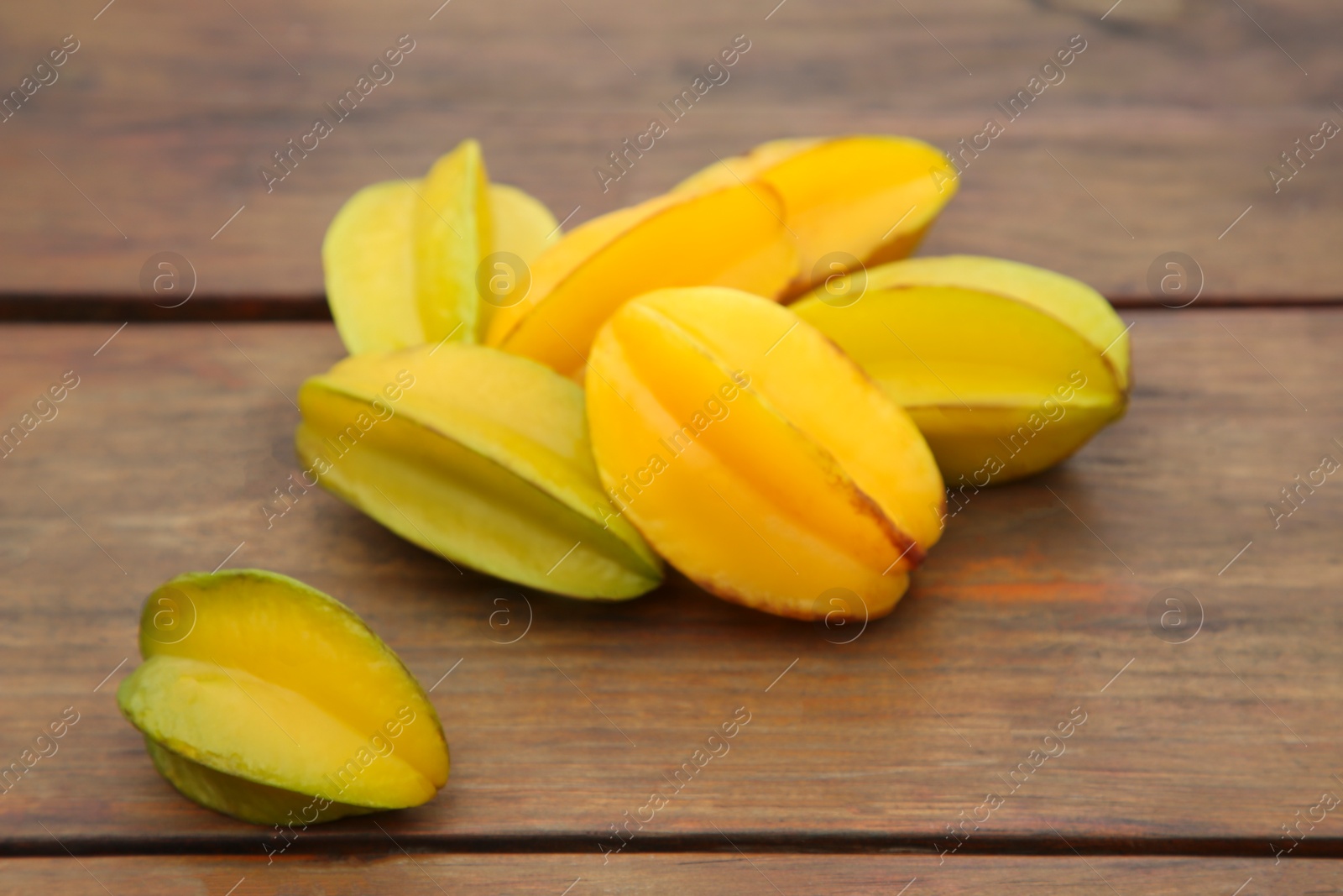 Photo of Delicious ripe carambolas on wooden table, closeup