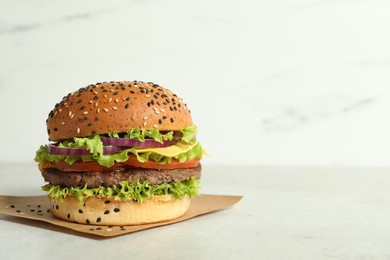 Photo of Burger with delicious patty on light table, space for text