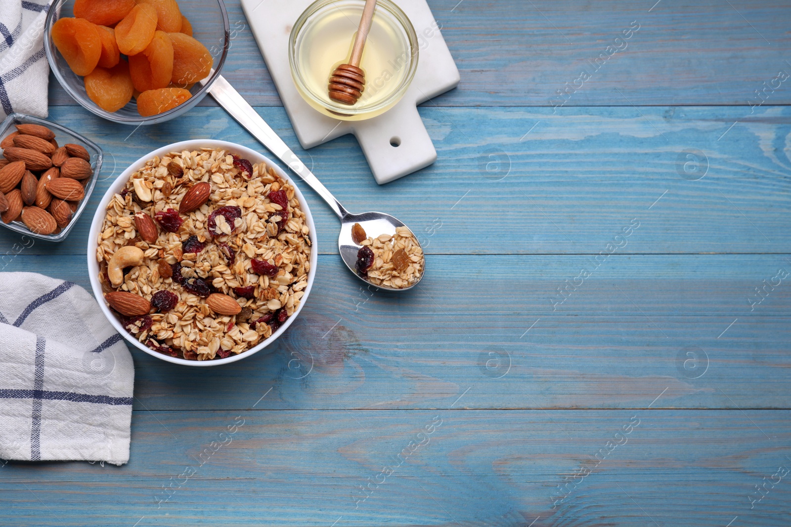 Photo of Tasty granola with nuts and dry fruits on light blue wooden table, flat lay. Space for text