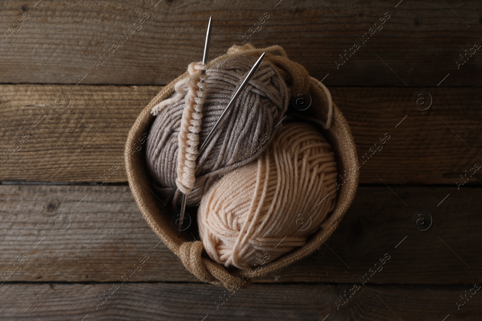Photo of Soft colorful yarns, knitting and metal needles on wooden table, top view