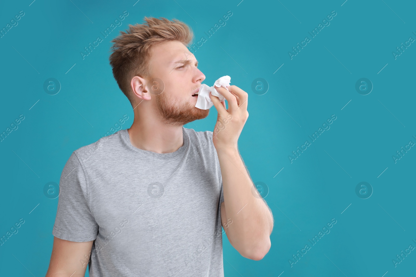 Photo of Young man suffering from allergy on blue background. Space for text