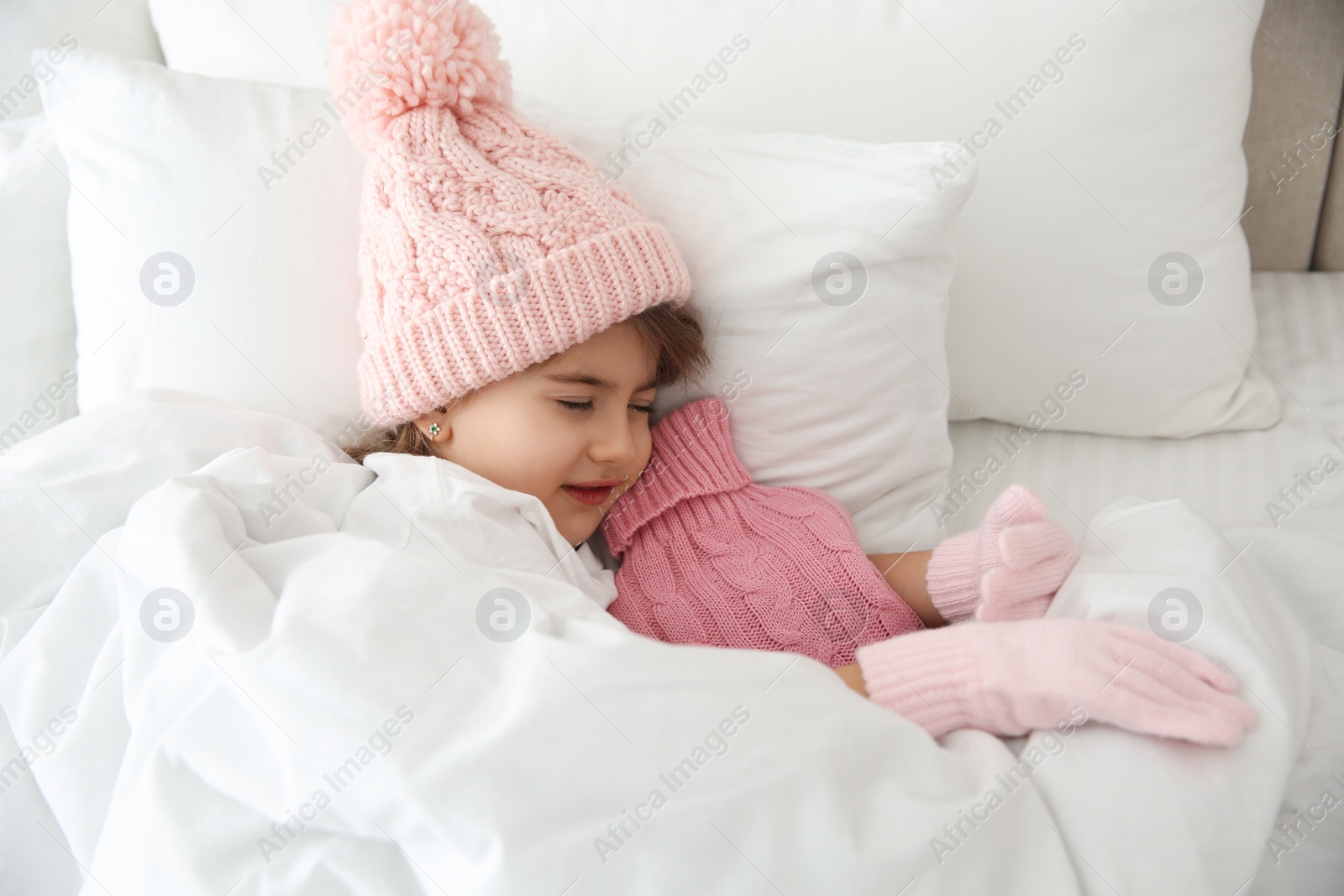 Photo of Ill girl with hot water bottle suffering from cold in bed at home