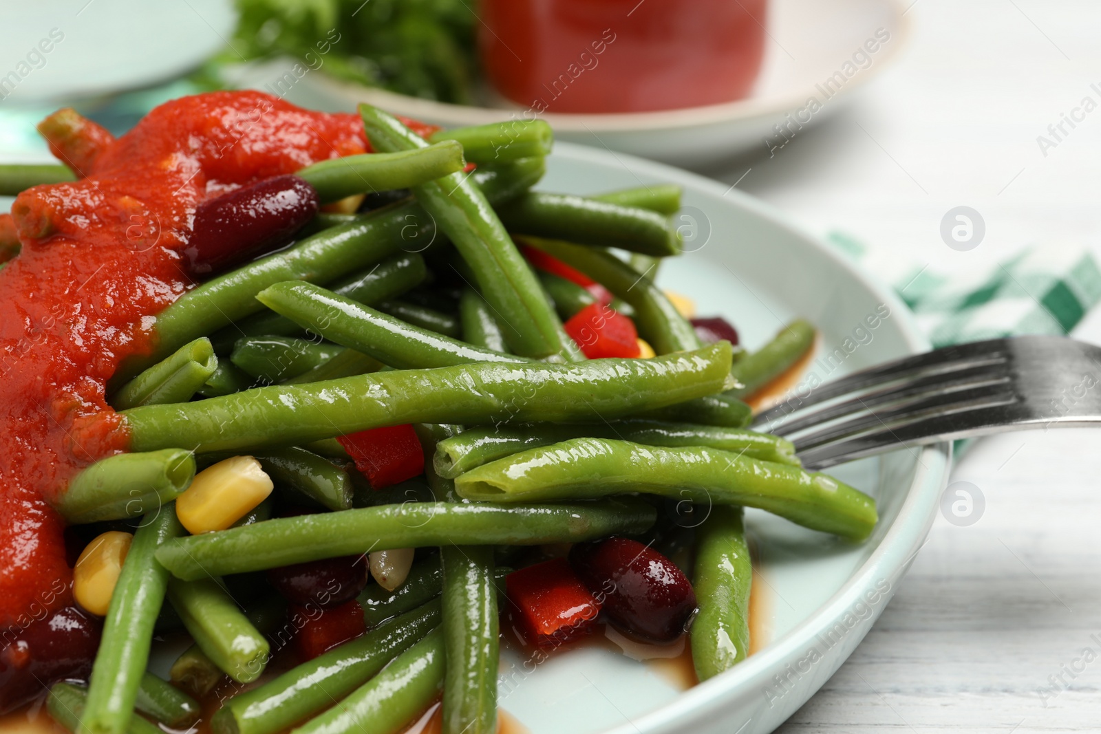 Photo of Delicious salad with green beans and tomato sauce served on white wooden table, closeup