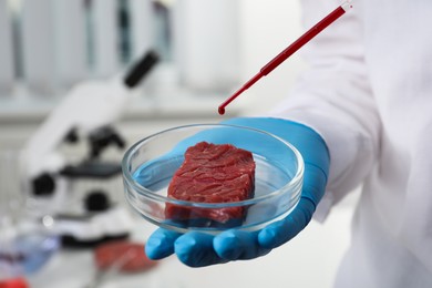 Photo of Scientist dripping red liquid onto cultured meat in laboratory, closeup