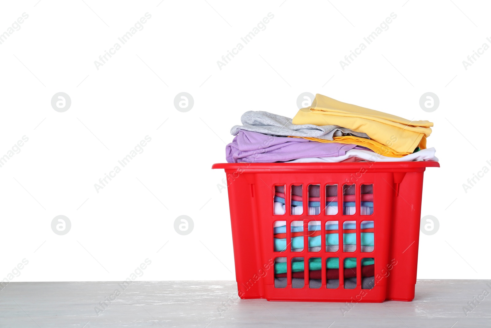 Photo of Basket with clean laundry on grey table, white background