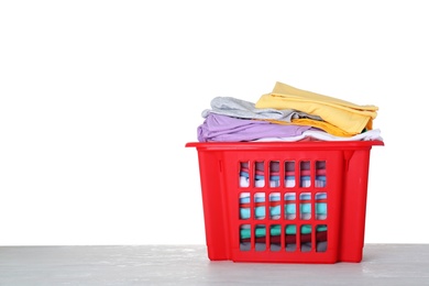 Photo of Basket with clean laundry on grey table, white background