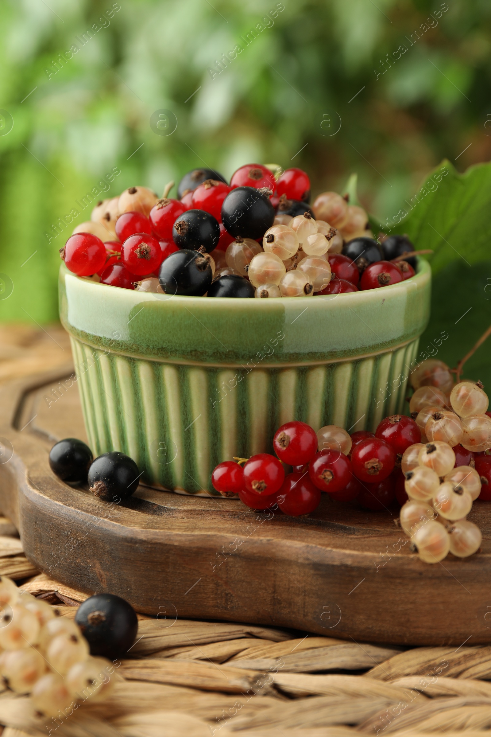 Photo of Different fresh ripe currants on wicker surface, closeup