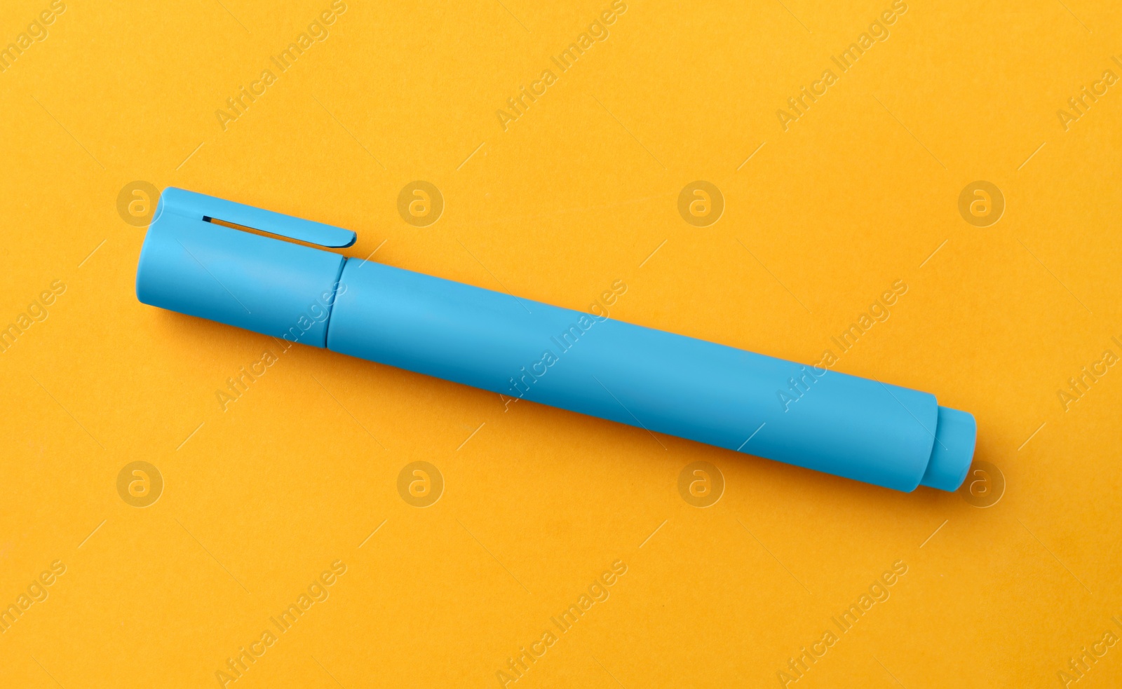 Photo of Bright light blue marker on orange background, top view