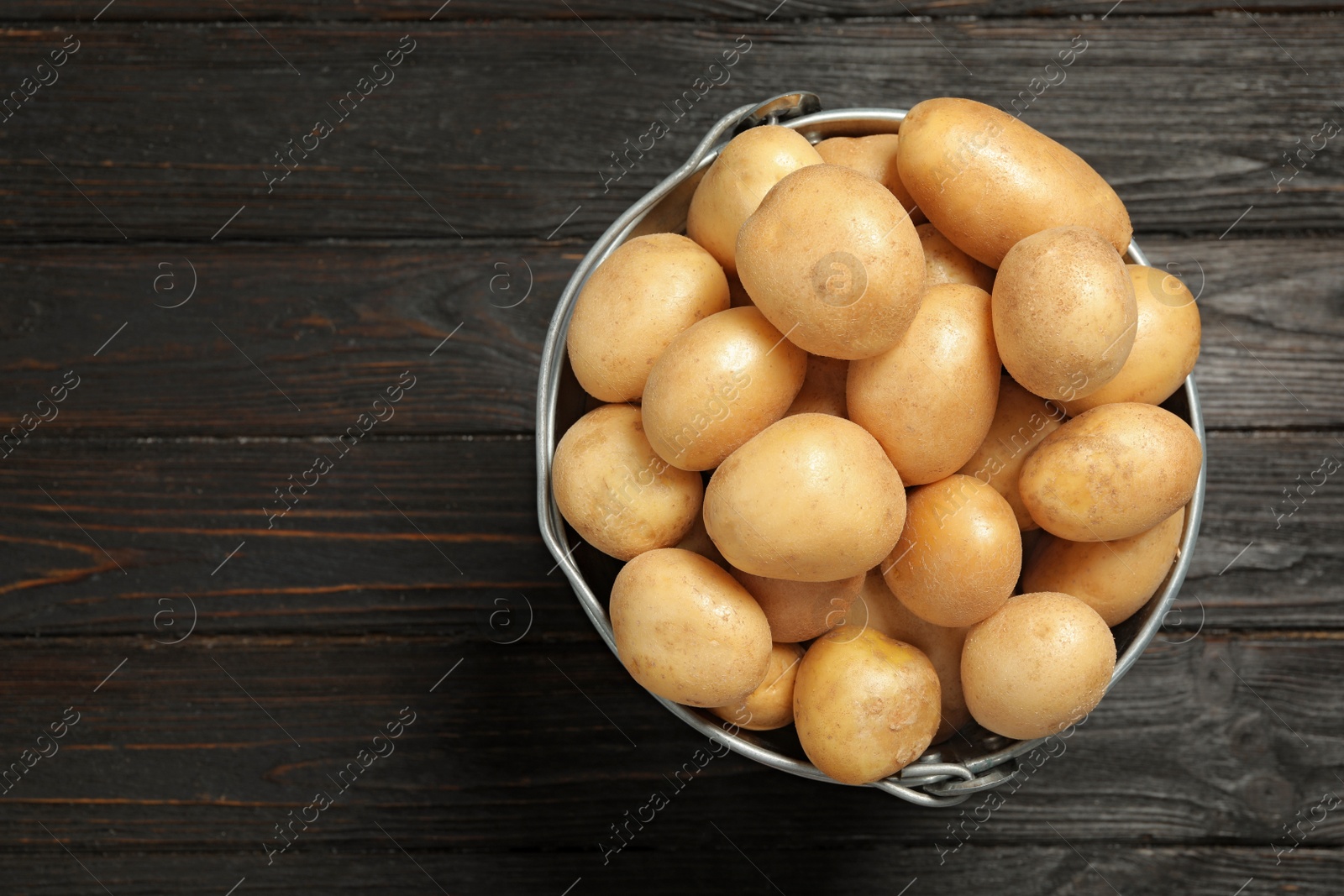 Photo of Raw fresh organic potatoes on black wooden background, top view. Space for text