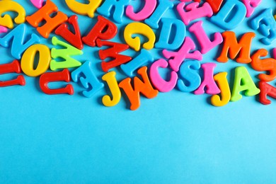 Photo of Many colorful magnetic letters on light blue background, flat lay. Space for text
