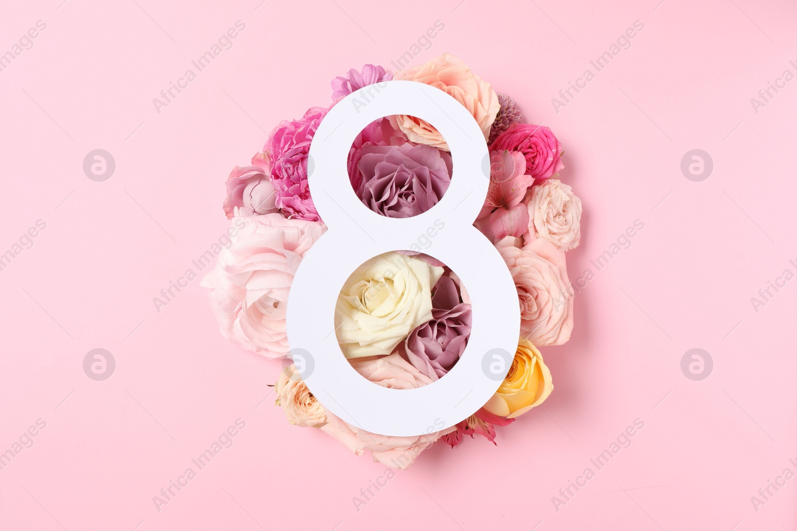 Photo of 8 March greeting card design with beautiful roses on light pink background, top view