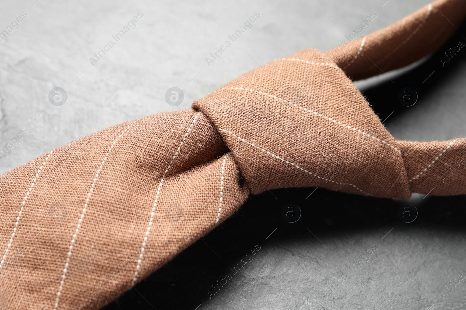 Photo of One striped necktie on grey textured table, closeup