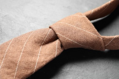 Photo of One striped necktie on grey textured table, closeup