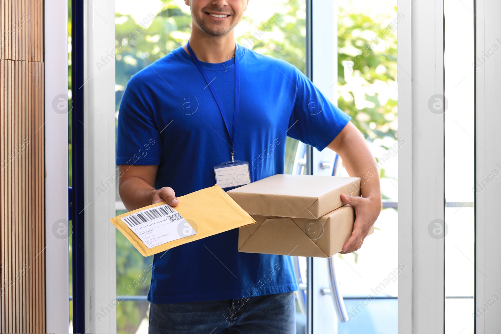 Photo of Young courier holding parcels on doorstep, closeup. Delivery service
