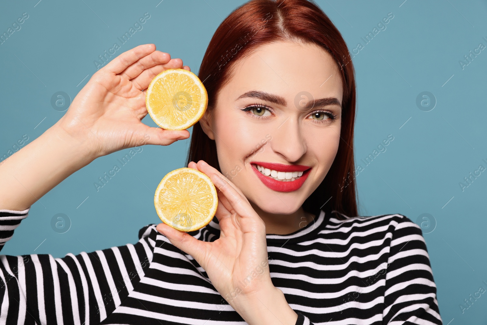 Photo of Happy woman with red dyed hair and lemons on light blue background
