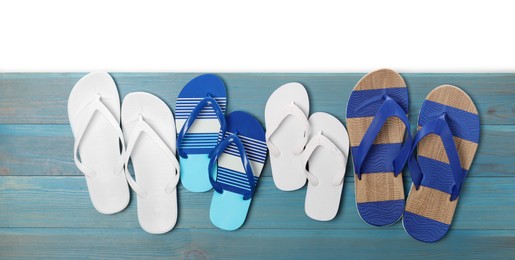 Photo of Different stylish flip flops on turquoise wooden table against white background, top view