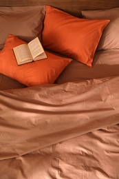 Book on bed with brown and orange linens