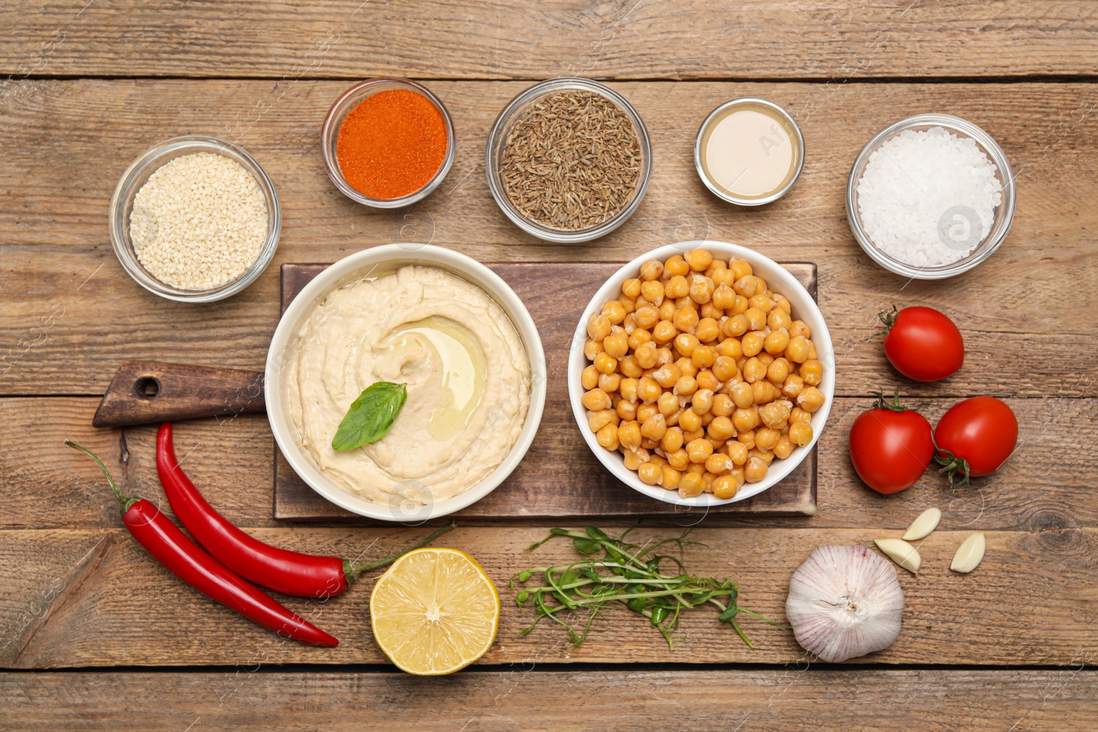 Photo of Bowl with delicious hummus and different ingredients on wooden table, flat lay