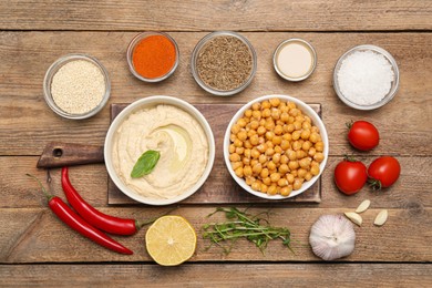 Bowl with delicious hummus and different ingredients on wooden table, flat lay