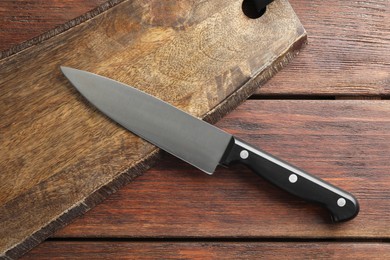 Photo of One sharp knife and board on wooden table, top view