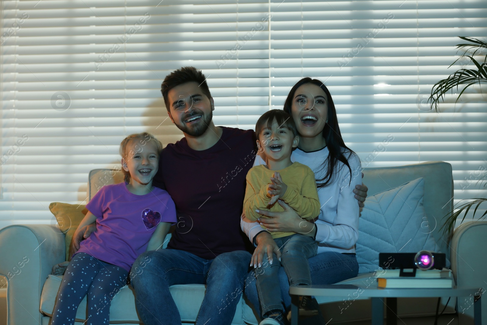 Photo of Happy family watching movie using video projector at home