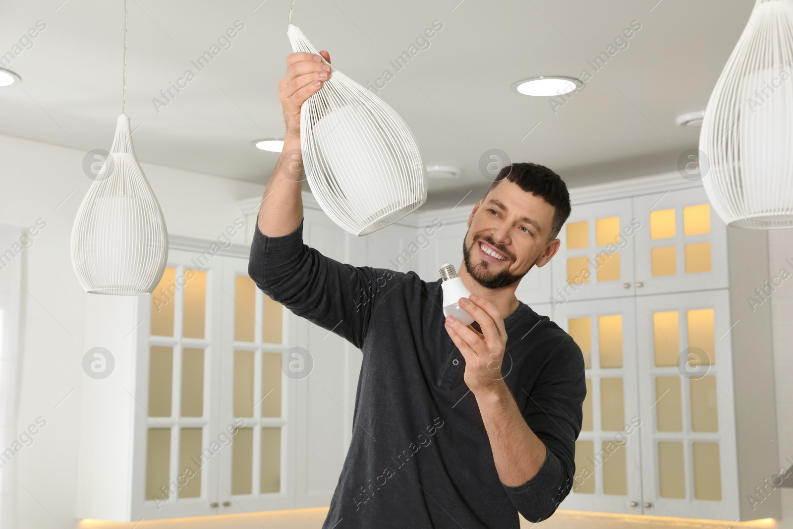 Photo of Man changing light bulb in lamp at home