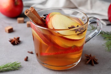 Photo of Aromatic hot mulled cider on grey table, closeup