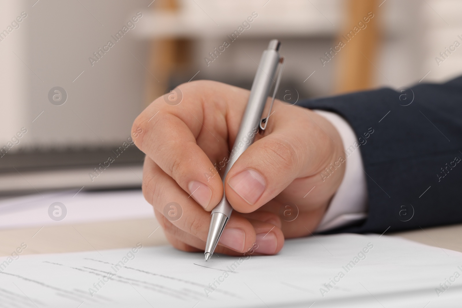 Photo of Man signing document at table, closeup view