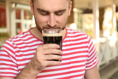 Photo of Handsome man with cold kvass outdoors, closeup. Traditional Russian summer drink