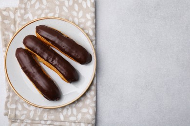 Photo of Delicious eclairs covered with chocolate on grey table, top view. Space for text
