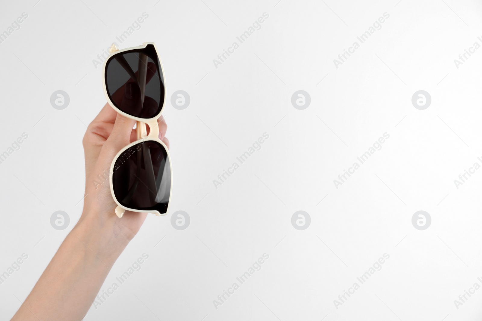 Photo of Woman holding stylish sunglasses on white background, closeup. Space for text