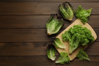 Different sorts of lettuce on wooden table, flat lay. Space for text