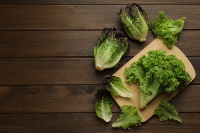 Photo of Different sorts of lettuce on wooden table, flat lay. Space for text