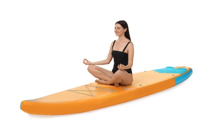 Photo of Happy woman practicing yoga on orange SUP board against white background