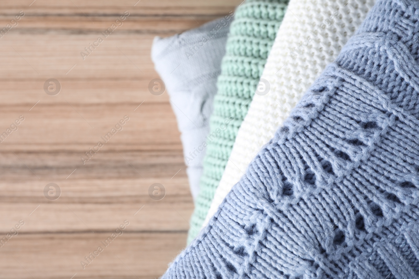 Image of Stack of folded warm sweaters on wooden table, top view