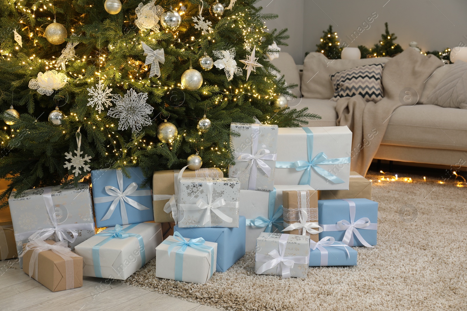 Photo of Many gift boxes under decorated Christmas tree in room