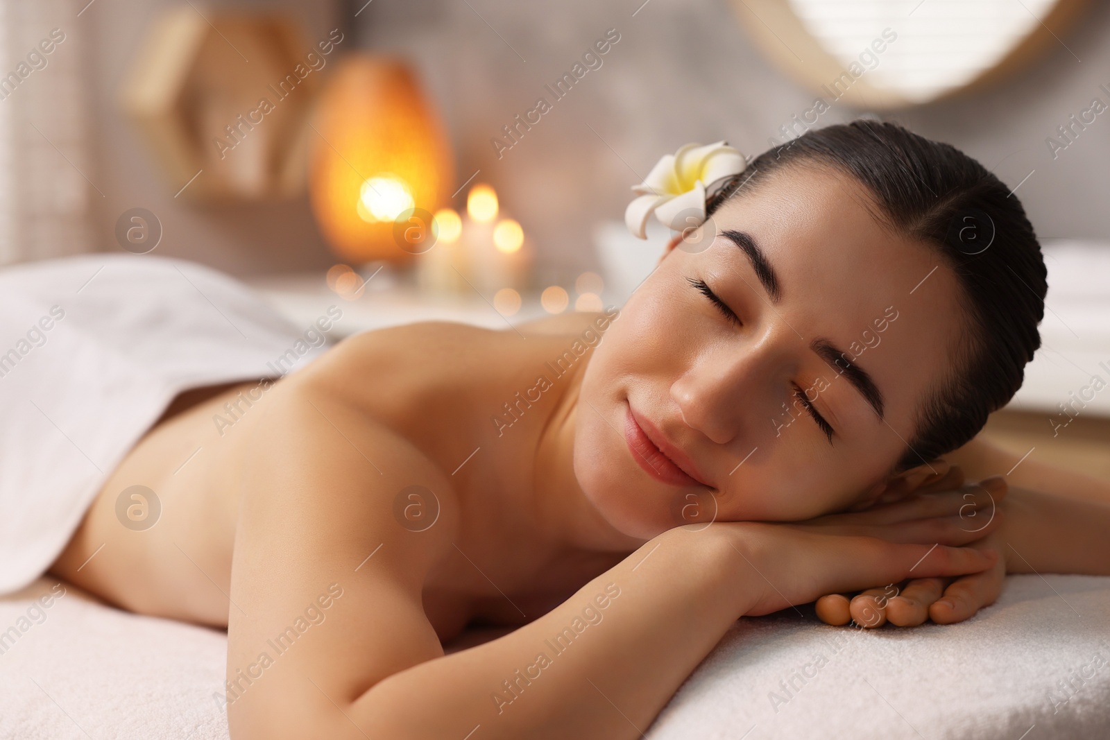 Photo of Beautiful woman relaxing on massage couch in spa salon