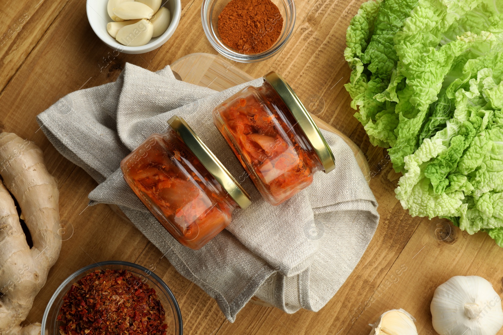 Photo of Delicious kimchi with Chinese cabbage and ingredients on wooden table, flat lay