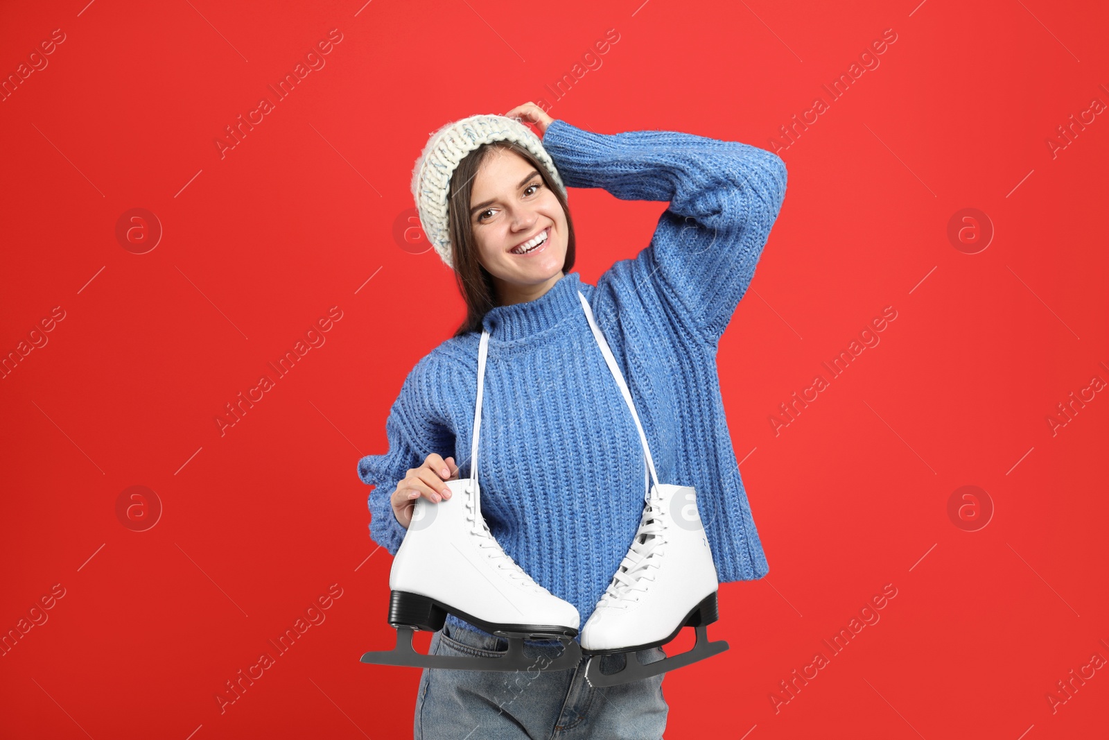 Photo of Happy woman with ice skates on red background