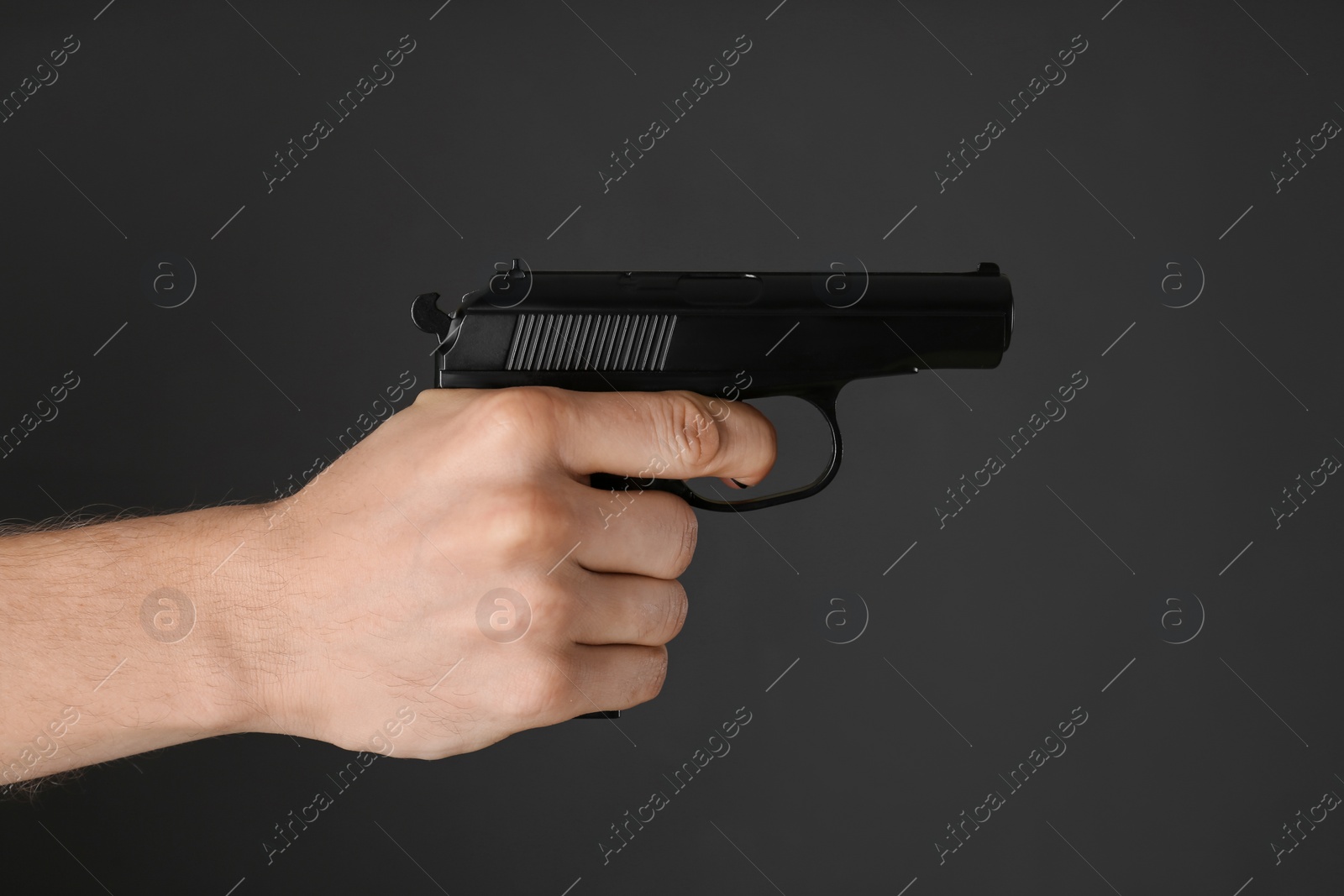 Photo of Man aiming gun on dark background, closeup